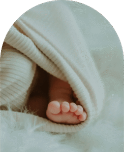 contact-hero-image-min Adorable tiny newborn baby feet wrapped in a soft blanket.