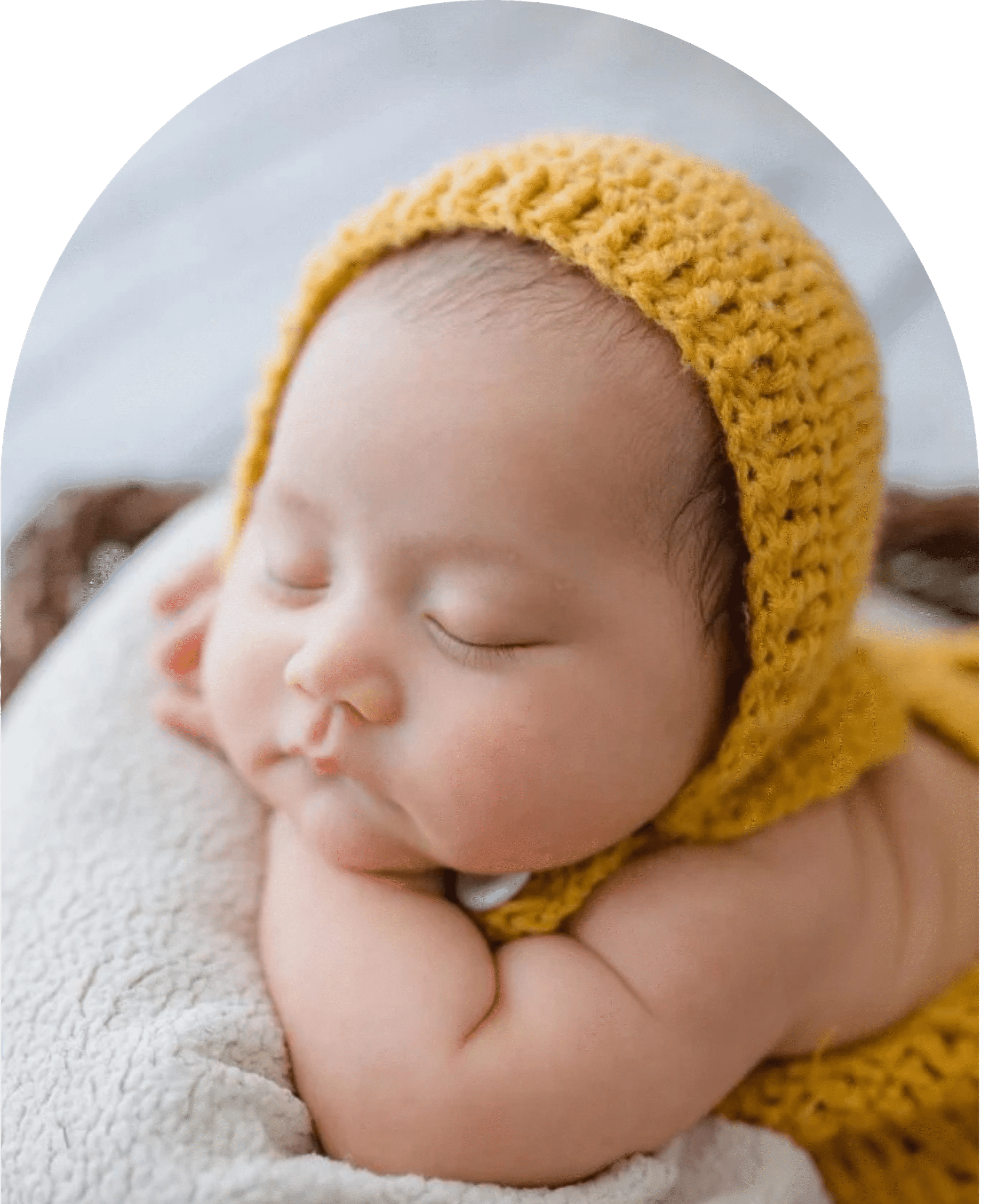 home-hero-image-min An adorable baby wearing a yellow knit sleeveless hoodie, sleeping on her tummy on a soft pillow.